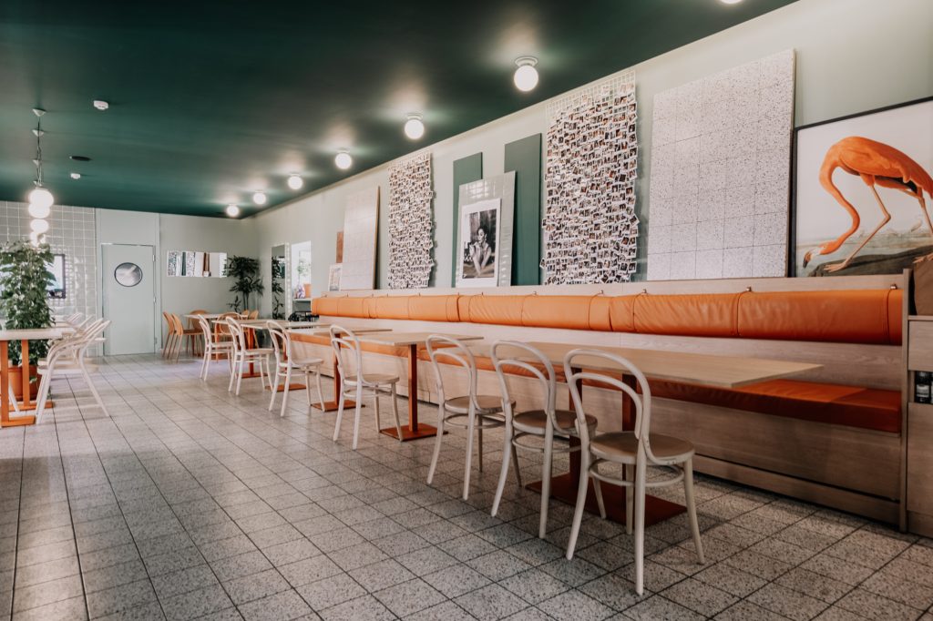 Elephant Shoe cafe restaurant interior design with a central bar and neutral tones and polaroid wall of fame